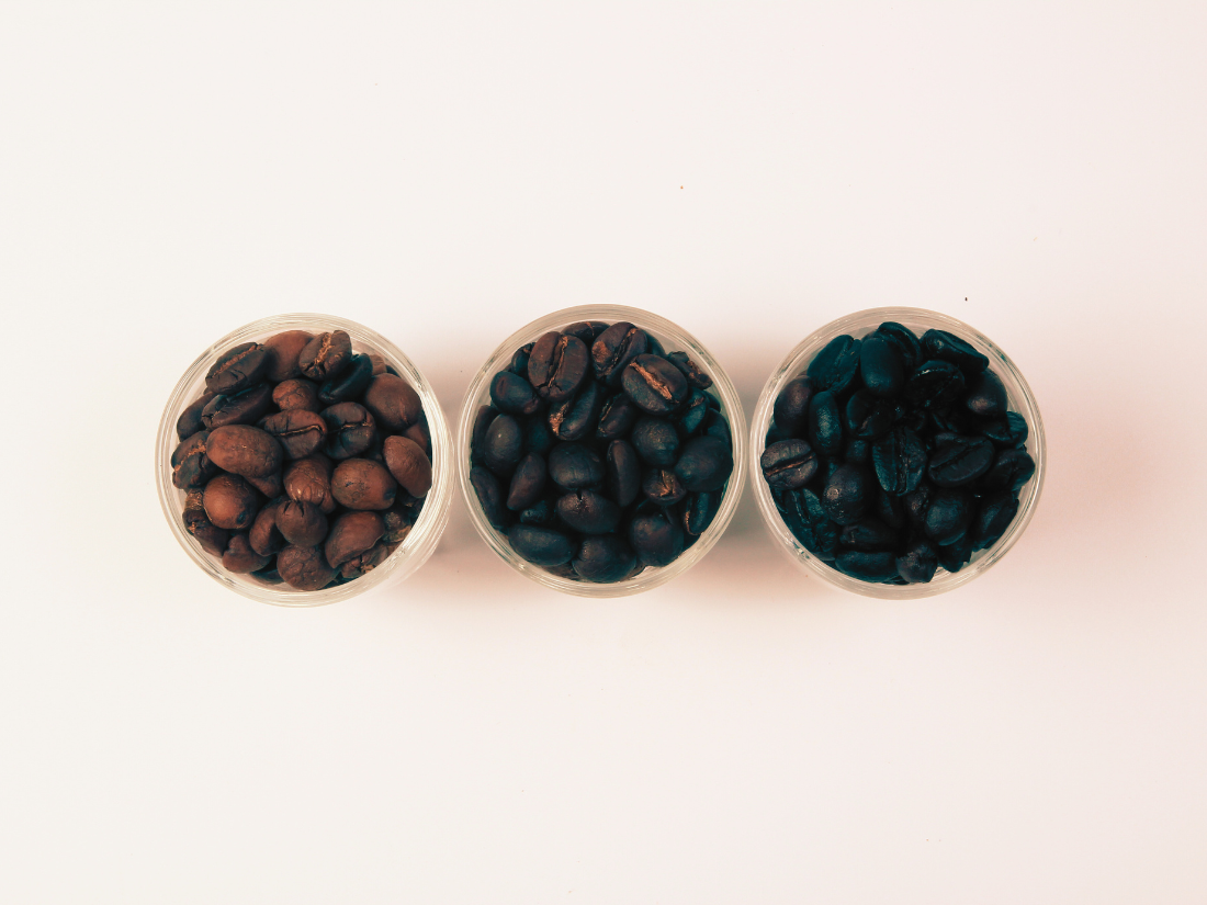 Three cups filled with light, medium, and dark roast coffee beans from Palm Beach Coffee Co
